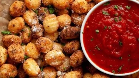 Plate of crispy air fryer gnocchi served with herbs and spices.
