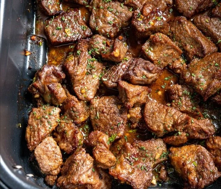 Garlic butter steak bites served on a plate with fresh herbs